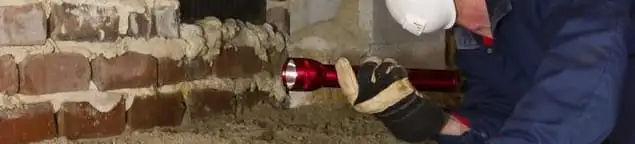 Pest control technician inspecting a crawl space for ant activity and entry points in Huntsville, AL