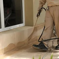 General pest control technician spraying exterior perimeter around a home in Huntsville, AL