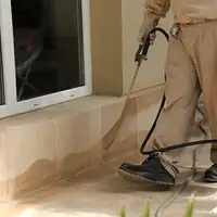 General pest control technician spraying exterior perimeter around a home in Huntsville, AL
