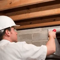 Termite inspection technician checking a basement wall and framing for termite activity in Huntsville, AL