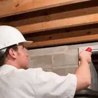 Termite inspection technician checking a basement wall and framing for termite activity in Huntsville, AL